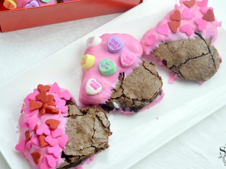 Valentine's Day Fudgy Brownies on plate. A from-scratch Valentine's Day Fudgy Brownie recipe, stuffed with butterscotch chips. Dipped in chocolate and then topped with candy hearts and sprinkles.