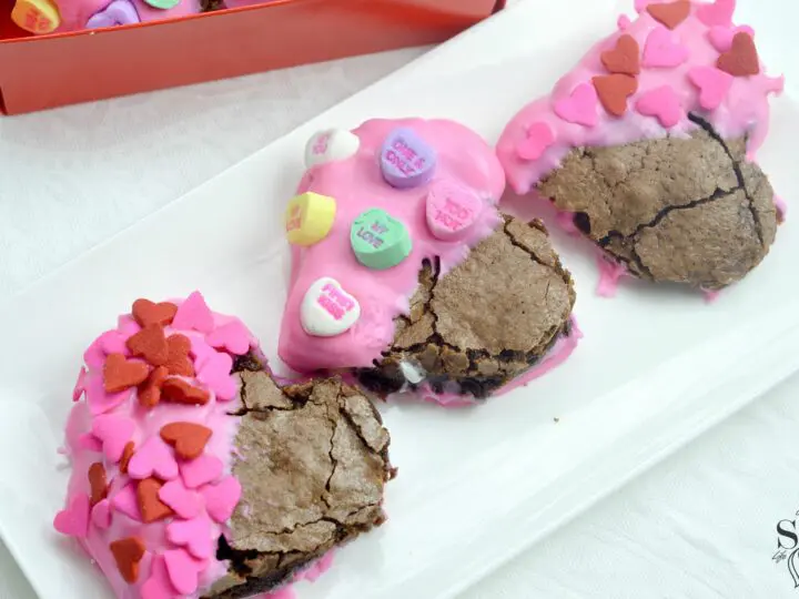Valentine's Day Fudgy Brownies on plate. A from-scratch Valentine's Day Fudgy Brownie recipe, stuffed with butterscotch chips. Dipped in chocolate and then topped with candy hearts and sprinkles.