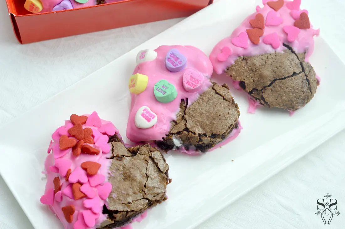 Valentine's Day Fudgy Brownies on plate. A from-scratch Valentine's Day Fudgy Brownie recipe, stuffed with butterscotch chips. Dipped in chocolate and then topped with candy hearts and sprinkles.