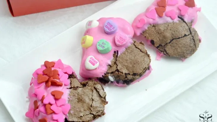 Valentine's Day Fudgy Brownies on plate. A from-scratch Valentine's Day Fudgy Brownie recipe, stuffed with butterscotch chips. Dipped in chocolate and then topped with candy hearts and sprinkles.
