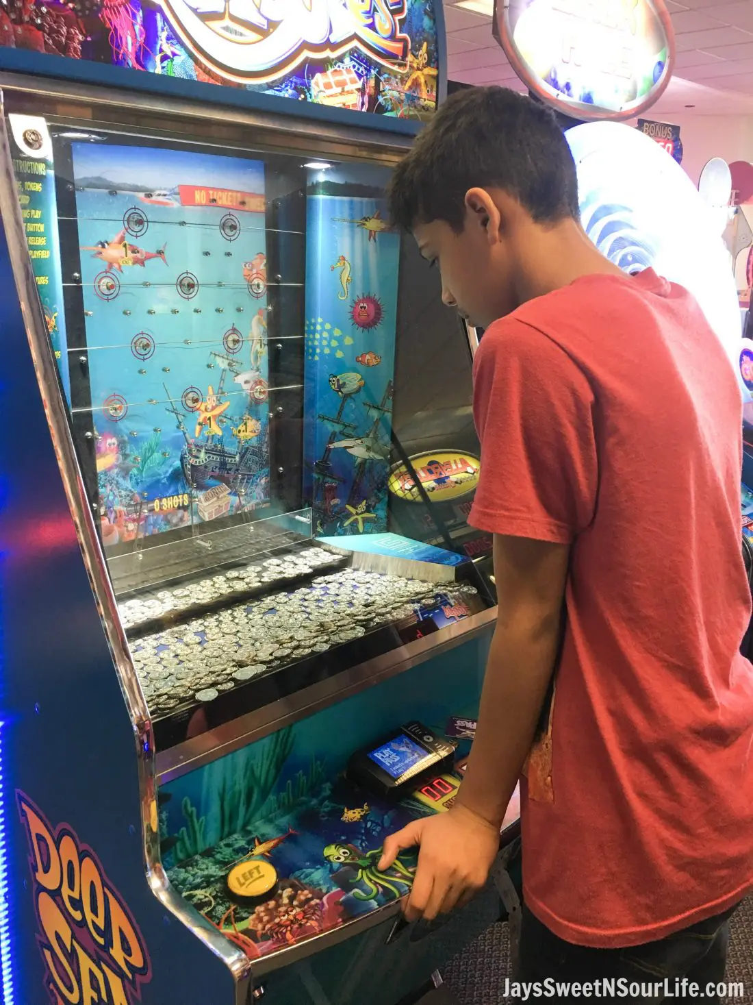 Chuck e cheeses VIP birthday party offers 2 hour of unlimited game play. African american boy playing fish coin game and winning tickets.