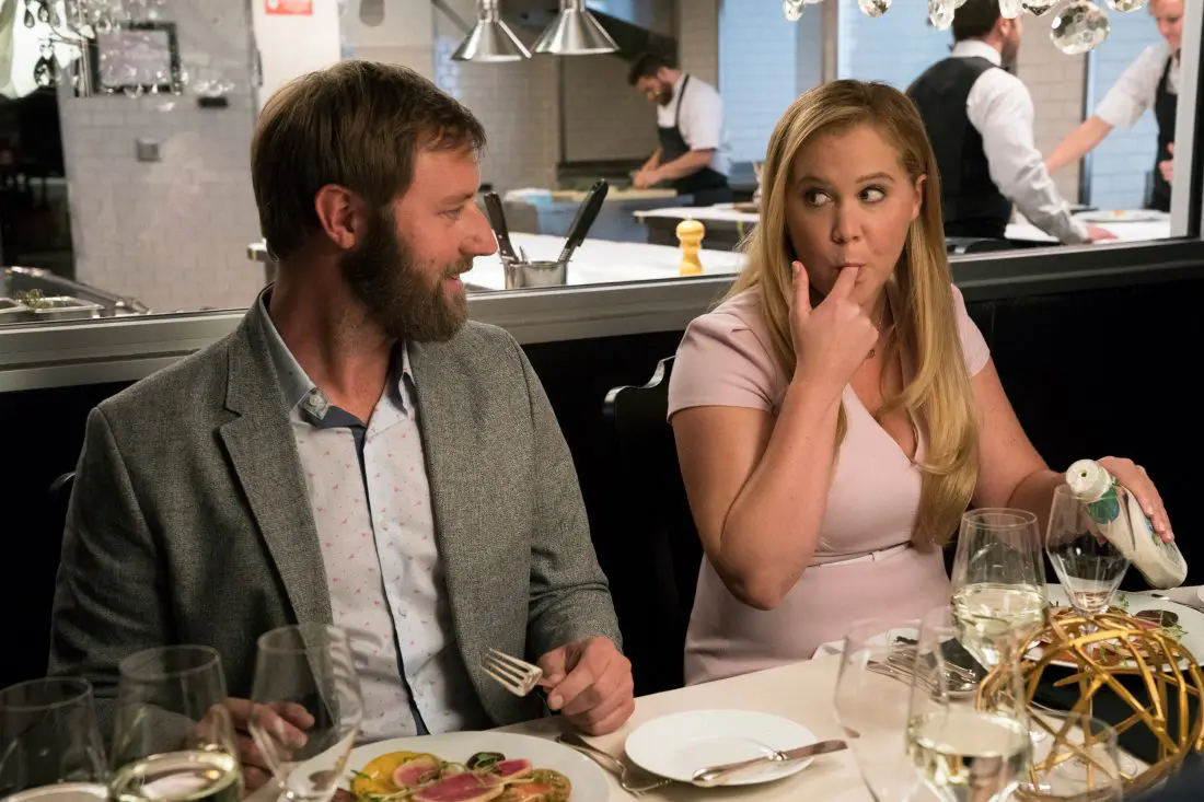 Amy and a man sitting at a table In I FEEL PRETTY an ordinary woman who struggles with feelings of insecurity and inadequacy on a daily basis wakes from a fall believing she is suddenly the most beautiful and capable woman on the planet. In Theaters everywhere April 20th, 2018.