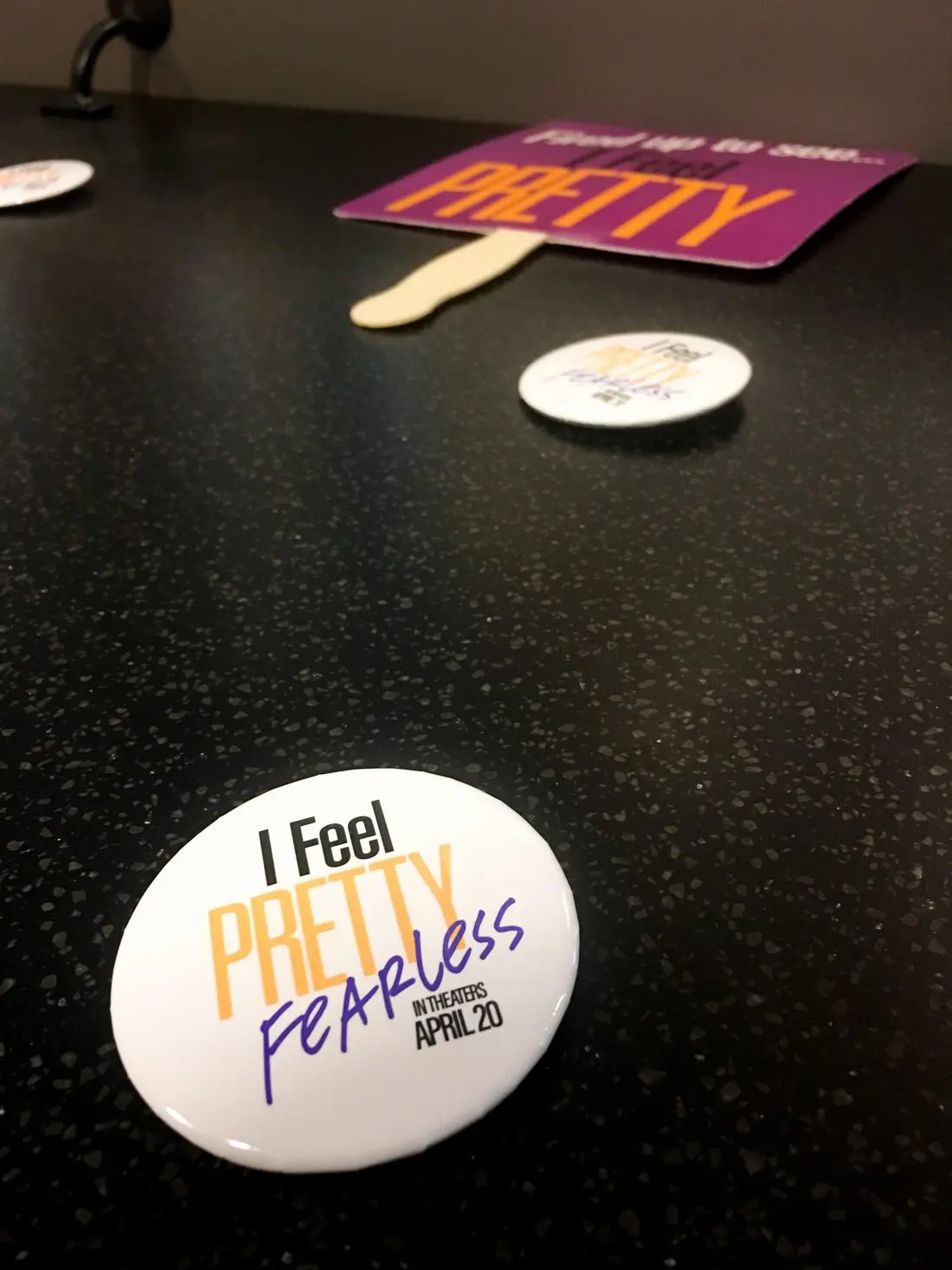 I Feel Pretty Fearless Button on table. The I Feel Pretty Film is in theaters everywhere today.