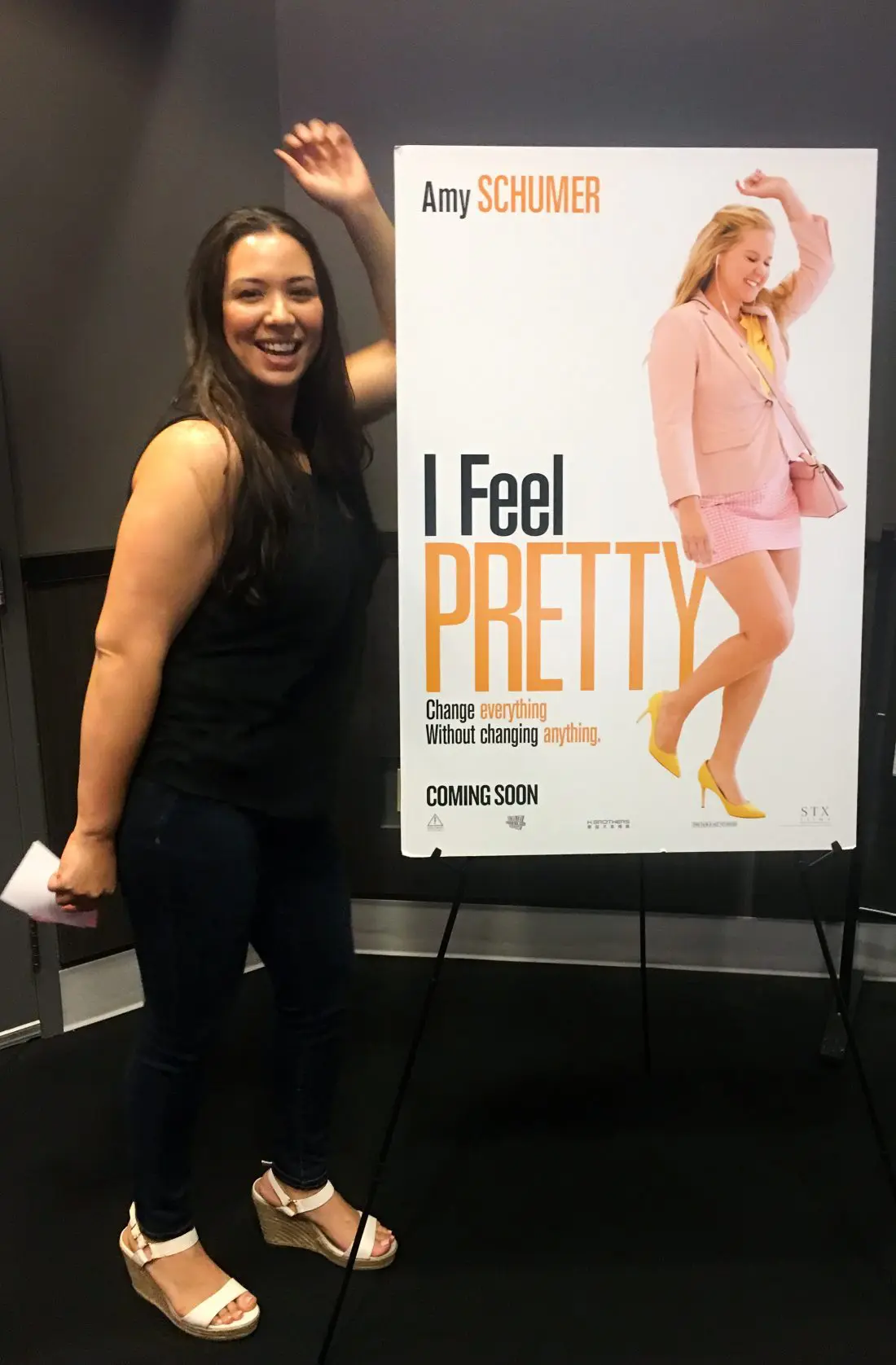 Filipino Woman standing in front of I Feel Pretty Movie Poster. The I Feel Pretty Film is in theaters everywhere today.