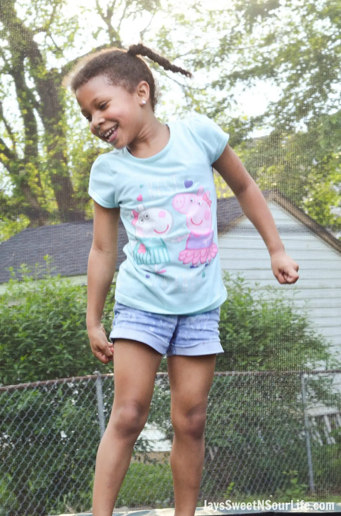 Little african american girl smiling and jumping on a trampoline. Attending a Beach Sundae Party.
