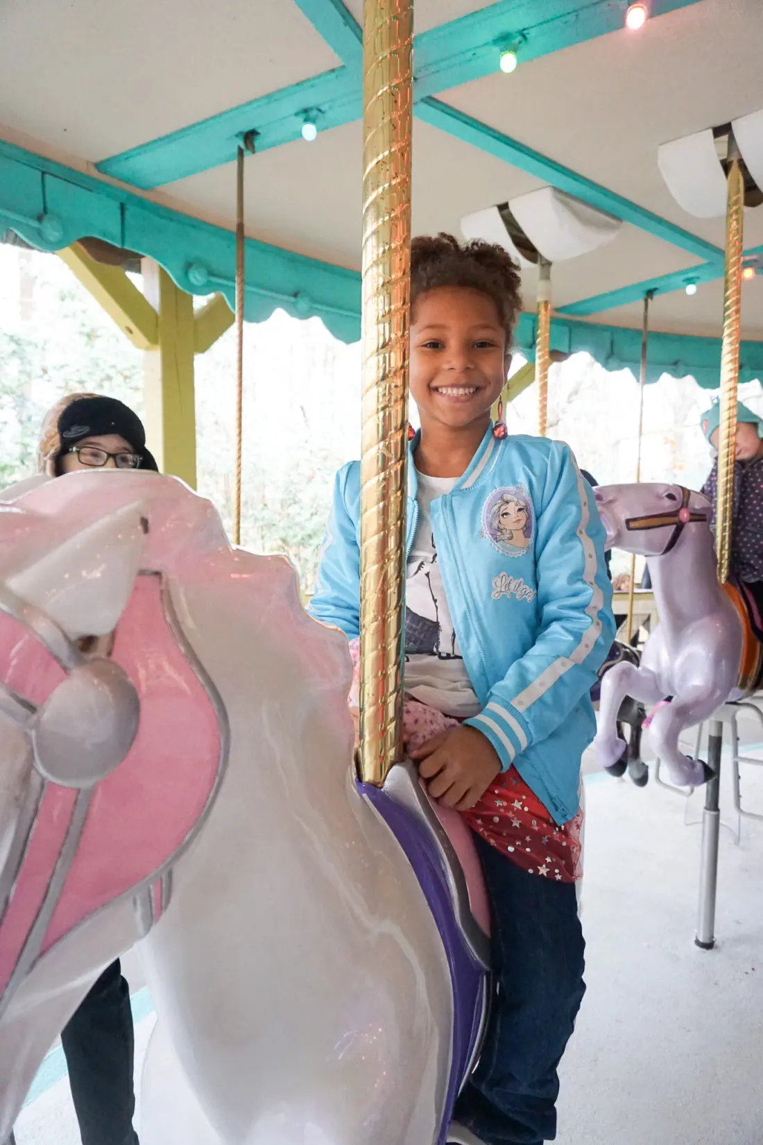 Little Girl Riding Carosel 15 Instagram Worthy Walls Christmas Town Busch Gardens. Instagram Worthy Walls and Locations around Busch Gardens Christmas Town in&nbsp;Williamsburg&nbsp;Virginia.