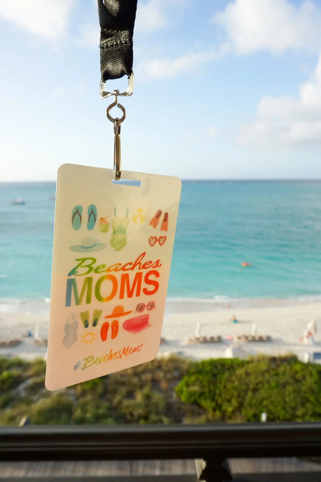 2018 Beaches Moms Badge in front of the ocean at Beaches Resorts in Turks and Caicos. Read all about my international adventure with my family on my blog now.
