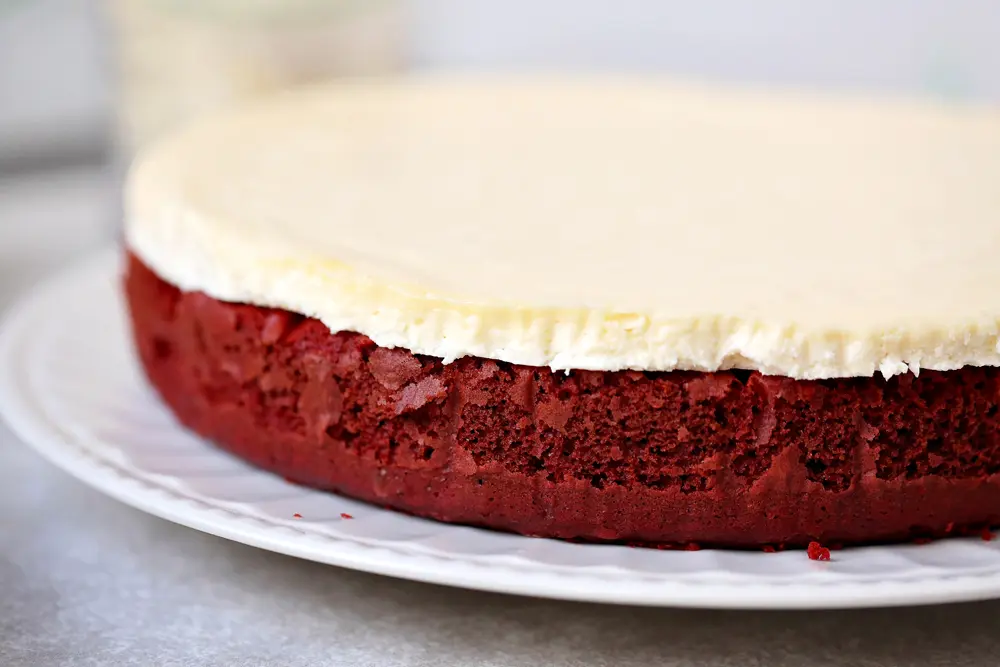 This beautiful 2 layered Red Velvet Cheesecake is made with a moist red velvet cake and a smooth, creamy cheesecake layer on the top. It's as if a cake and cheesecake had a baby, both layers made with love and topped with a cream cheese frosting.