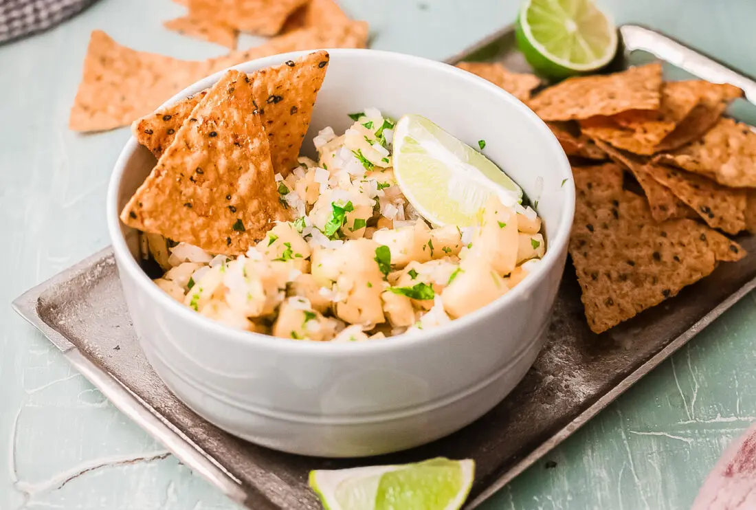 Easy pineapple salsa dip in bowl with tortilla chips. On platter and ready to be served.
