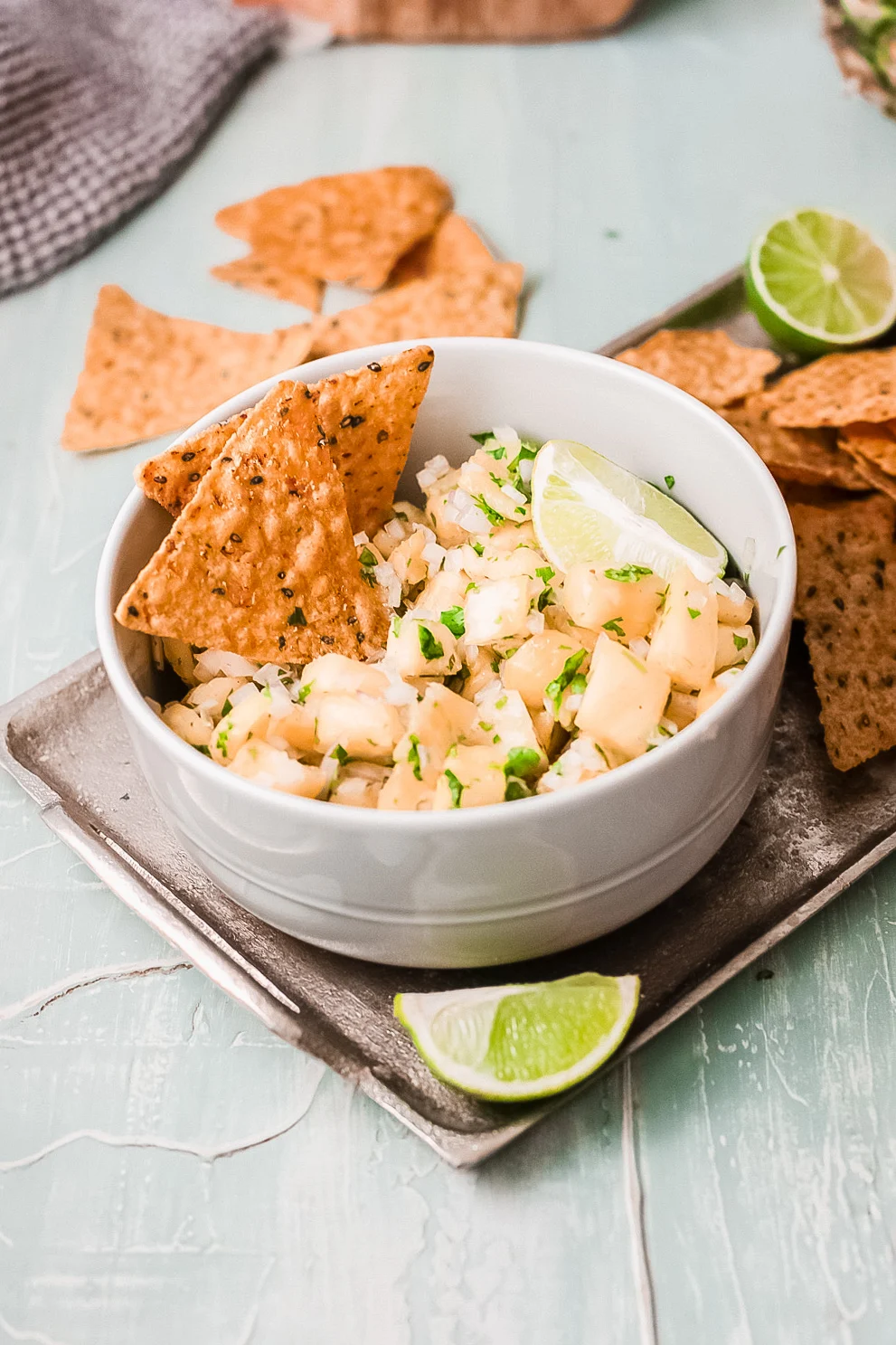 pineapple salsa dip in bowl with tortilla chips. On platter and ready to be served.