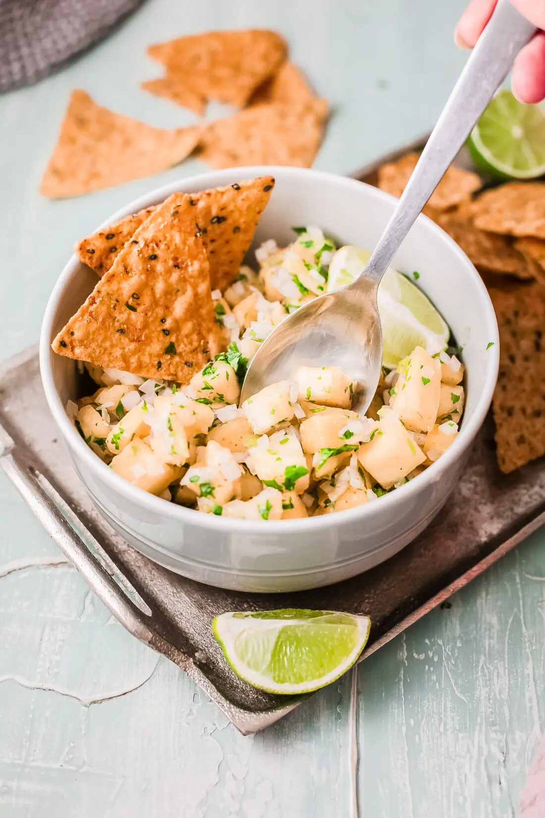 Easy to follow pineapple salsa dip in bowl with a spoon and tortilla chips. On platter and ready to be served.