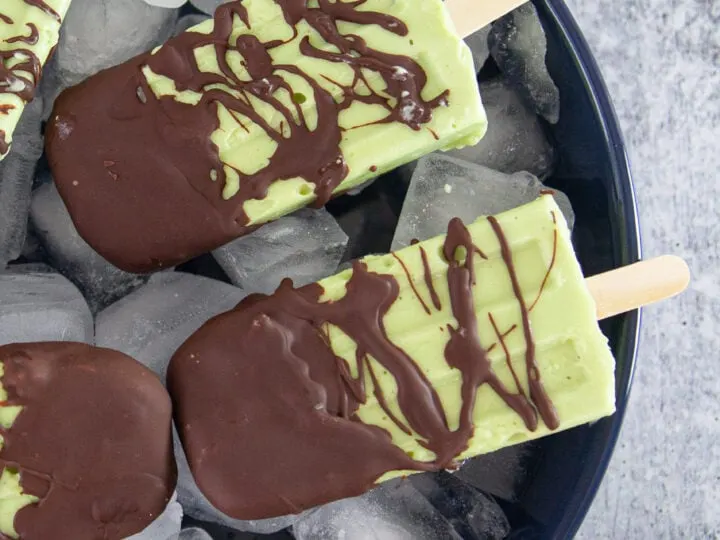 These creamy avocado popsicles are hand-dipped into dark chocolate, the perfect refreshing hot summer day treat. This easy, creamy and delicious Chocolate Dipped Avocado Popsicle recipe is perfect pool parties and group get-togethers.